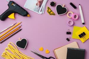 Crafting supplies arranged on a pink background, including glue gun, scissors, and decorative items for DIY projects photo