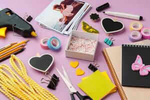 Crafting supplies arranged on a pink background, including glue gun, scissors, and decorative items for DIY projects photo