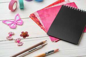 Crafting essentials on a workspace featuring a black notebook, colorful paper, and decorative supplies photo