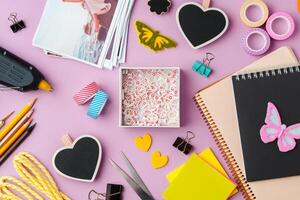 Crafting supplies arranged on a pink background, including glue gun, scissors, and decorative items for DIY projects photo