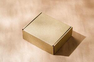 A plain cardboard box on a textured surface with soft light and shadows during the afternoon photo
