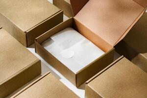 Brown cardboard box with a blank envelope on a light background in a well-lit setting photo