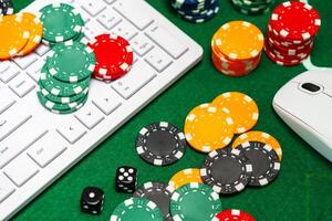 Chips and playing cards on a green felt surface near a computer keyboard during an online gaming session at home photo