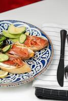 Freshly made open-faced sandwiches topped with smoked salmon and cucumber, served with a side salad photo