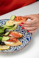 Woman enjoying a snack of smoked salmon and cucumber on toast with a fresh salad photo