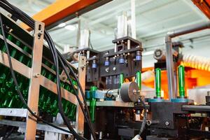 Machine assembling green glass bottles in a factory during daylight hours photo