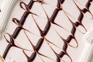 Delicious dessert featuring creamy vanilla ice cream swirled with chocolate sauce and topped with icing photo