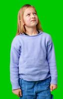 A young child in a light purple sweater gazes against a green background while deep in thought photo