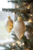 Close-up of a Christmas tree with a golden ornament and blurred lights in the background. Shiny glass decorations hang from the evergreen branches. Golden bokeh light effect. photo