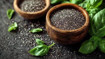 Fresh basil leaves complement the shiny black seeds in rustic wooden bowls photo