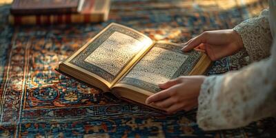 Hands holding open a book with Arabic calligraphy, resting on a patterned carpet with books photo
