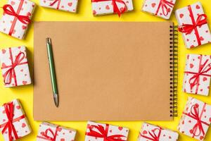 Top view of notebook surrounded with gift boxes colorful background. Valentine's Day concept photo