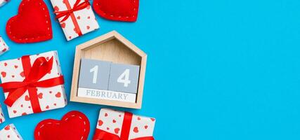 Holiday composition of gift boxes, wooden and red textile hearts on colorful background with empty space for your design. The fourteenth of February. Top view of Valentine's Day concept photo