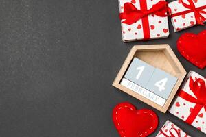 Holiday composition of gift boxes, wooden calendar red textile hearts on colorful background with empty space for your design. The fourteenth of February. Top view of Valentine's Day concept photo