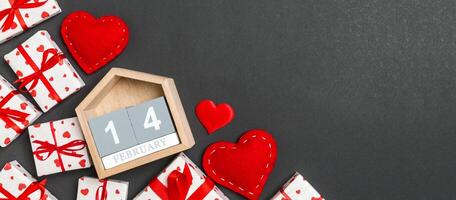 Top view of gift boxes, wooden calendar and red textile hearts colorful background. The fourteenth of february. St Valentine's day concept with copy space photo