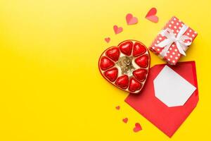 Envelope on colored background Valentine Day with gift box and chocolate. Heart shaped with gift box of chocolates top view with copy space photo