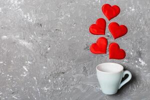 Top view of a cup and red hearts falling out from it on background. Happy Valentine's Day concept photo