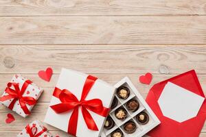Envelope colored background for Valentine Day box and chocolate. Heart shaped with gift box of chocolates top view with copy space photo