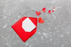 Red paper envelope empty white card and heart colored background. top view photo
