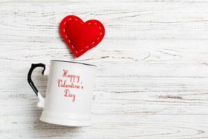 Top view of a cup and red hearts falling out from photo