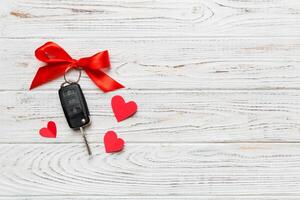 Car key with a red bow and on Colored table. Giving present or gift for valentine day or christmas, Top view with copy space photo