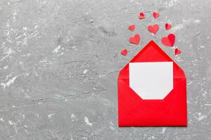 Red paper envelope with empty white card and heart background. top view valentines day concept photo