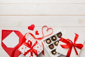 Envelope on colored for Valentine Day with gift box and chocolate. Heart shaped with gift box of chocolates top view with copy space photo