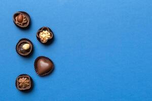 Different kinds of chocolates on colored table close-up. View and Flat Lay with copy space photo