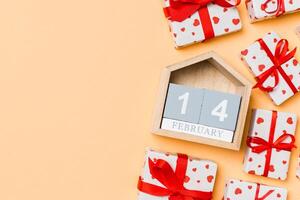 Holiday composition gift boxes with red hearts and wooden calendar on colorful background with empty space for your design. The fourteenth of February. Top view of Valentine's Day concept photo