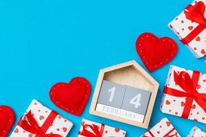 Top view of gift boxes, wooden calendar and red hearts on colorful background. The fourteenth of february. St Valentine's day concept with copy space photo