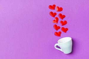 Top view composition red hearts falling out from a cup on colorful background with copy space. Romantic relationship concept. St Valentaine's Day photo