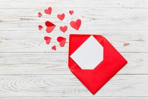 Red paper envelope with empty white card and colored background. top view valentines day concept photo