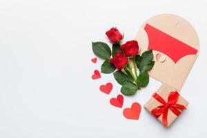 Valentine day composition with envelope rose flower and red heart on table. Top view, flat lay, copy space Holiday concept photo