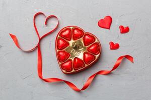 Delicious chocolate pralines red box for Valentine Day. Heart shaped box of chocolates top view with copy space photo