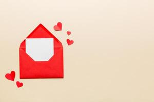 Red paper envelope with empty card and heart colored background. top view valentines day concept photo