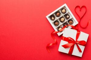 Delicious chocolate pralines red box for Valentine's Day. Heart shaped box of chocolates top view with copy space photo