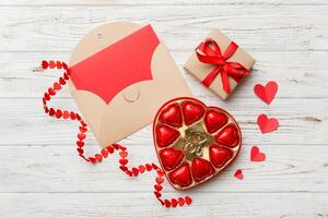 Envelope on colored background for Valentine Day with gift box and chocolate. Heart shaped with gift box of chocolates top view copy space photo