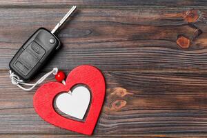 Top view of car key and heart a present for Valentine's day on wooden background. Romance concept with copy space photo
