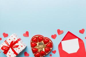 Envelope colored background for Valentine Day with gift box and chocolate. Heart shaped with gift box of chocolates top view with copy space photo