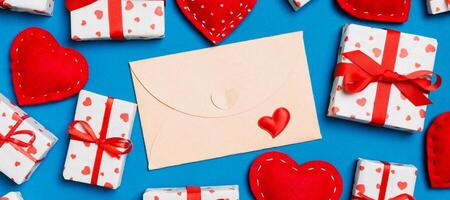 Top view of colorful background made of craft envelope, gift boxes and red textile hearts. Valentine's Day concept photo