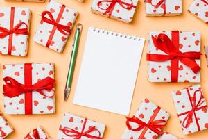 Holiday composition notebook and gift boxes with red hearts on colorful background with empty space for your design. Top view of Valentine's Day concept photo