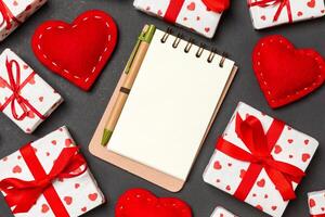 Top view of notebook white gift boxes and red textile hearts on colorful background. Valentine's Day concept photo
