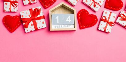 Top view of gift boxes, wooden calendar red textile hearts on colorful background. The fourteenth of february. St Valentine's day concept with copy space photo
