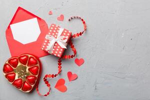 Envelope colored background for Valentine Day gift box and chocolate. Heart shaped with gift box of chocolates top view with copy space photo