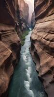 A vertical shot of a river flowing through a narrow canyon, with rugged rock walls and blank areas for text. photo