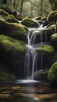 A vertical view of water running down a rocky waterfall, adorned with moss, and blank space for text placement. photo