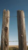 A close-up vertical of weathered wooden fence posts standing in a quiet rural area, with ample space for design or text. photo