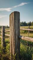 A vertical shot of aged wooden fence posts in a tranquil rural environment, with a blank sky or background for easy text placement. photo