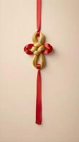 A simple, elegant design of a golden Chinese knot with a red ribbon, placed on a smooth, light-colored surface, leaving room for a message. photo