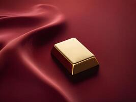 A tranquil image of a gold ingot positioned delicately on velvet fabric in deep red and gold shades, providing plenty of empty space for text placement. photo